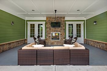A patio with a wicker sofa and a stone fireplace.